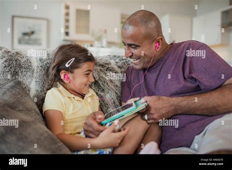 Father And Daughter Laughing Together Using A Digital Touch Screen