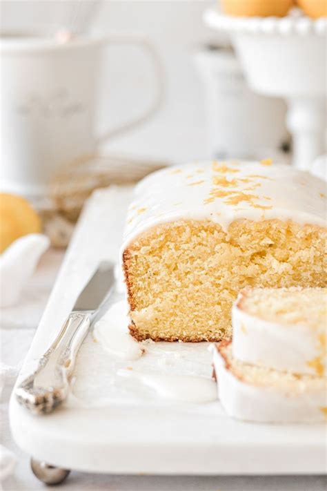 A Slice Of Cake With Icing On A White Plate Next To Some Oranges