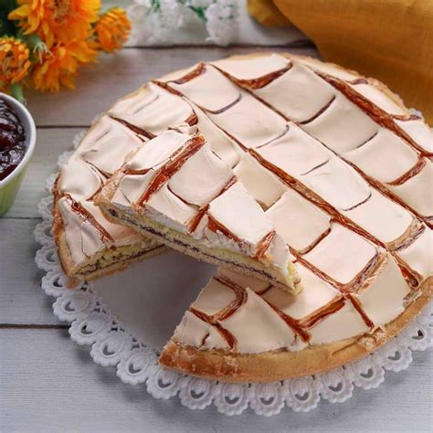 A White Cake Sitting On Top Of A Lace Doily Next To A Bowl Of Fruit