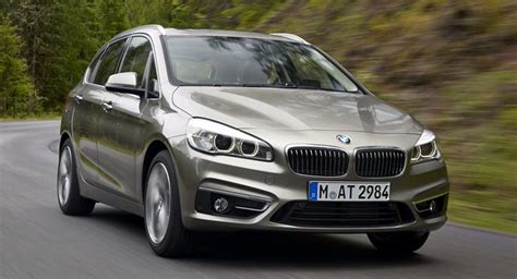 A Silver Bmw Car Driving Down A Road