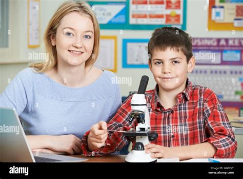 Teacher With Male Student Using Microscope In Science Class Stock Photo