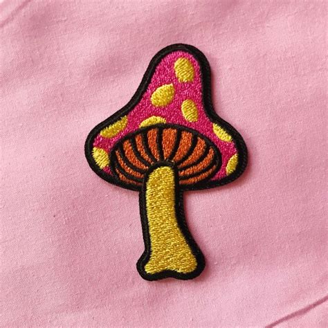 A Pink Shirt With A Yellow And Red Mushroom Patch On The Front