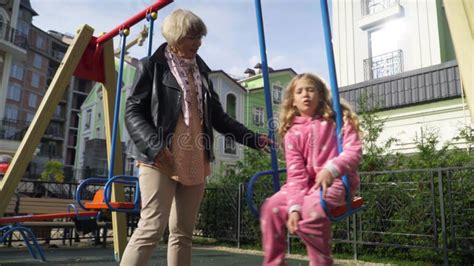 Portrait Of Happy Caucasian Slim Beautiful Granny Swinging Swings With Pretty Girl Sitting