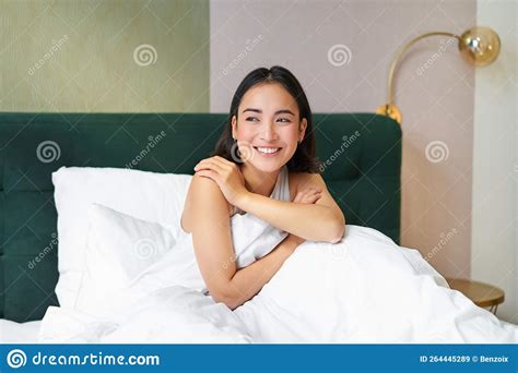 Happy Mornings Smiling Asian Woman Wakes Up In Her Bed Looks Outside