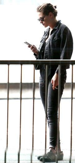 A Woman In Black Jacket And Jeans Looking At Her Cell Phone While