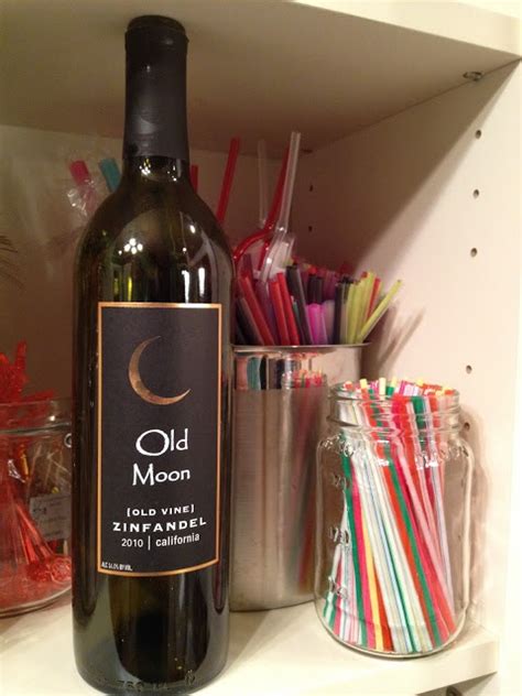 A Bottle Of Wine Sitting On Top Of A Shelf Next To Cups And Straws