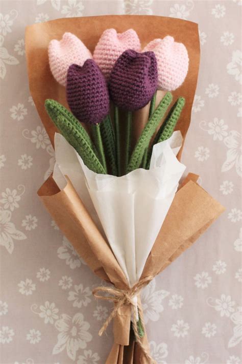 Three Crocheted Flowers Are Wrapped In Brown Paper