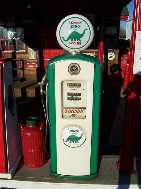 An Old Fashioned Gas Pump With A Dinosaur Sign On Top