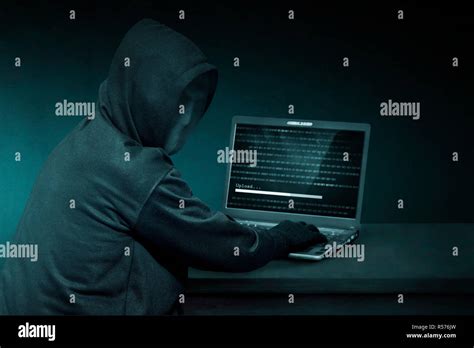 Hooded Hacker With Anonymous Mask Using Laptop To Steal Data Stock