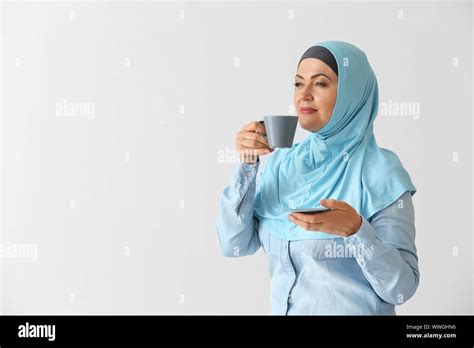 Beautiful Mature Muslim Woman With Cup Of Coffee On Light Background