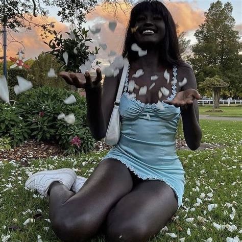 A Woman Sitting In The Grass With Her Hands Out And White Butterflies