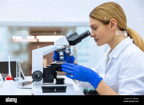 Blonde Scientist Working With Microscope Analyzes Petri Dish Sample