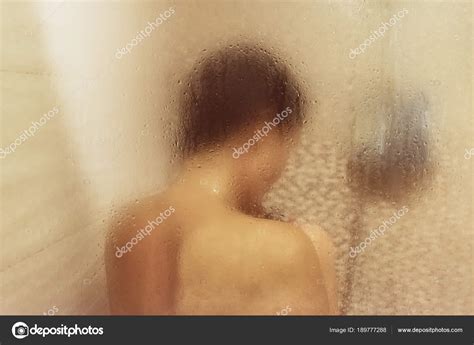 Hermosa mujer en la ducha detrás de vidrio con gotas Brillo amarillo