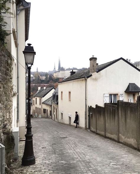 A Person Is Walking Down The Street In An Old Town With White Buildings