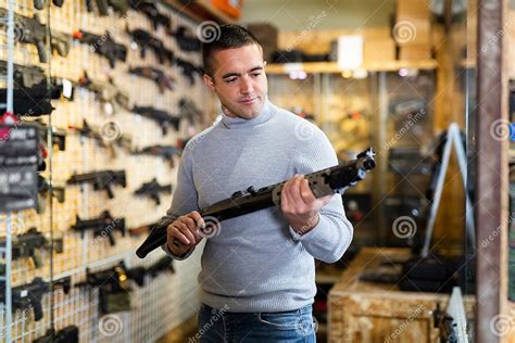 Middle Aged Man Chooses Pump Action Shotgun In Gun Store Stock Photo