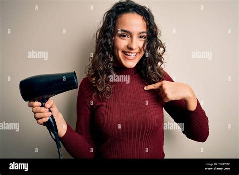 Young Beautiful Woman With Curly Hair Using Hair Dryer Over Isolated