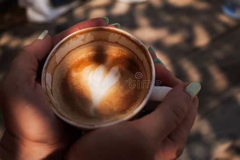 Woman Hands Holding Cup Of Cappuccino Coffee With Heart Shape Stock