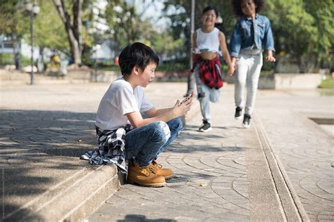 Cute Boy On His Phone While Two Of His Friends Are Approaching By Stocksy Contributor Jovo