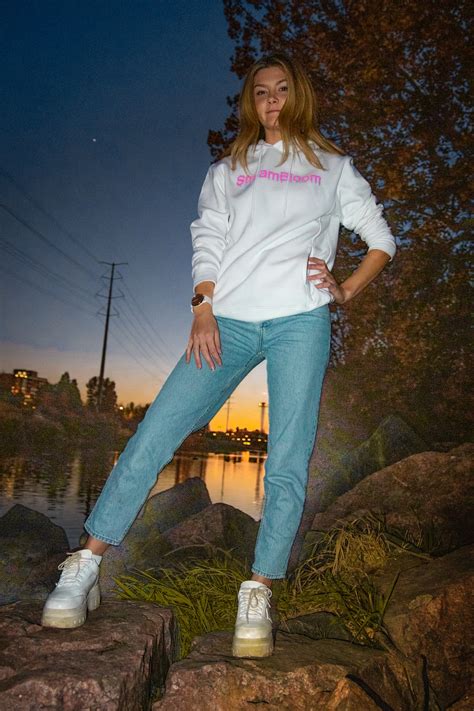 Woman In White Long Sleeve Shirt And Blue Denim Jeans Standing On Brown Rock Near Body Photo