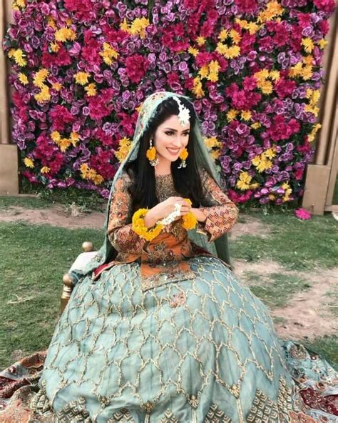 A Woman Sitting On Top Of A Grass Covered Field Next To Flowers In