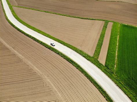 Aerial White Car Driving Down A Road Winding Through The Scenic