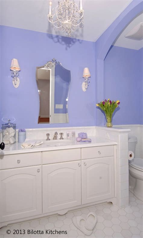 A Bathroom With Blue Walls And White Cabinets Chandelier Above The