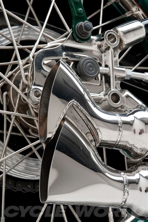 the front wheel of a motorcycle with chrome spokes and an exhaust pipe on it