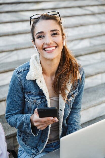 Premium Photo Smiling Young Woman Wearing Jacket Sitting On Stairs