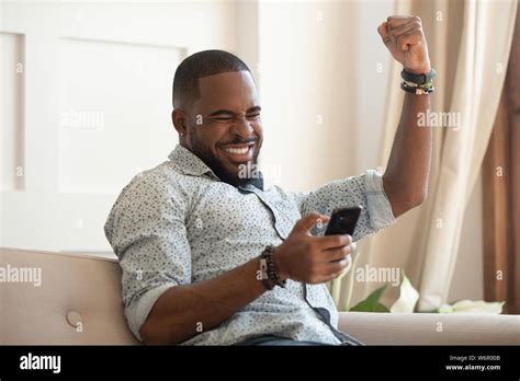 Overjoyed Black Man Holding Smartphone Feeling Euphoric With Mobile Win