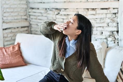Premium Photo Tired Chinese Woman Yawns On Sofa Seeking Rest
