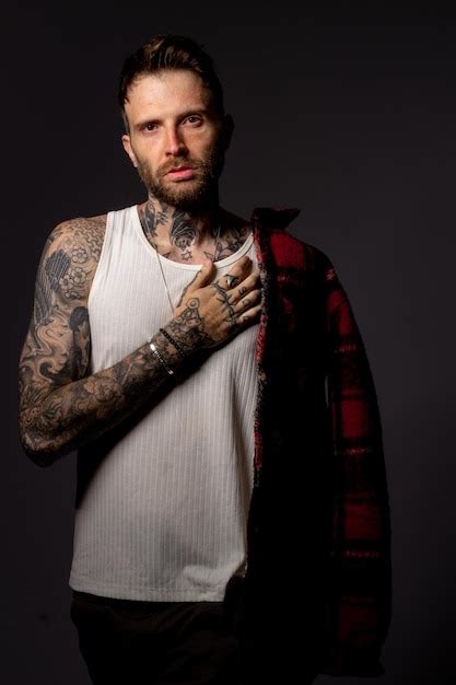 Premium Photo A Man With Tattoos On His Arms Stands In Front Of A Dark Background