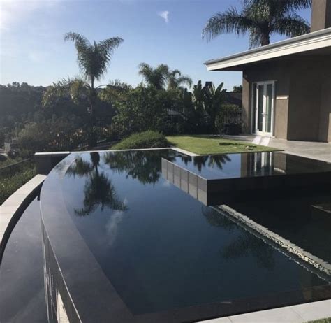 An Outdoor Swimming Pool In Front Of A House With Palm Trees On The