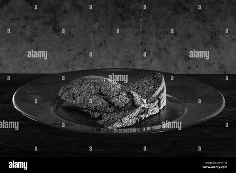 Two Small Pieces Of Bread On A Large Glass Plate Against A Rough Dirty