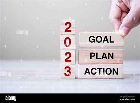 Hand Holding Wooden Block With Text 2023 GOAL PLAN And ACTION On Table