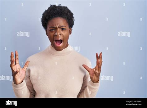 African American Woman Standing Over Blue Background Crazy And Mad Shouting And Yelling With