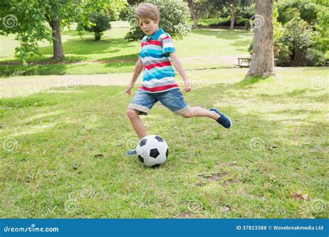 Comprimento Completo De Um Menino Que Retrocede A Bola No Parque Foto