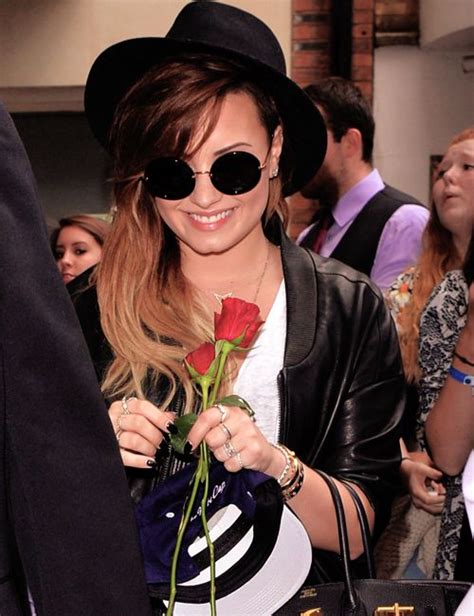 A Woman In Black Hat And Sunglasses Holding A Red Rose