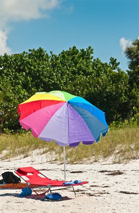 Single Colorful Beach Umbrella A Beach Lounge And Beach Shoes On A