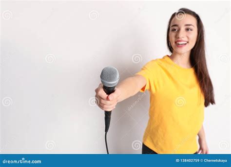 Young Woman Holding Microphone And Smiling On Color Background Stock