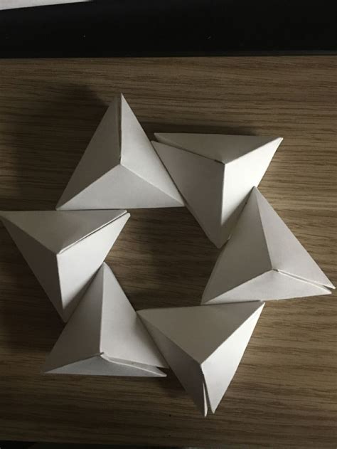 Four White Origami Shapes On A Wooden Surface