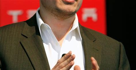 A Man In A Suit And White Shirt Is Giving A Speech With His Hands Together