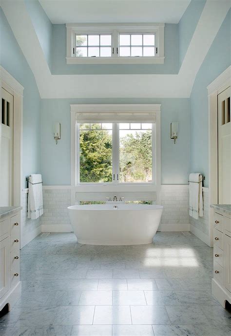 A Large White Bath Tub Sitting Under Two Windows