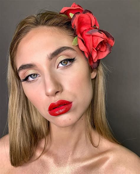 A Woman With Red Lipstick And A Flower In Her Hair Is Posing For The Camera