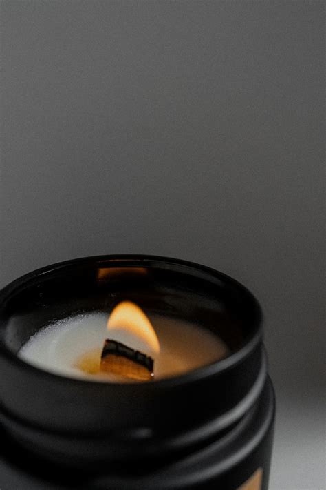 a lit candle sitting on top of a table next to a cup filled with liquid