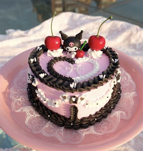 a heart - shaped cake with cherries on top sits on a pink platter