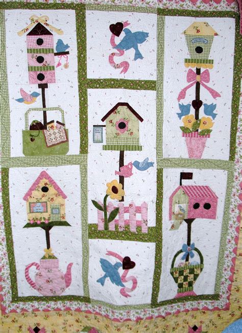 A Quilted Wall Hanging With Bird Houses And Flowers On Its Sides