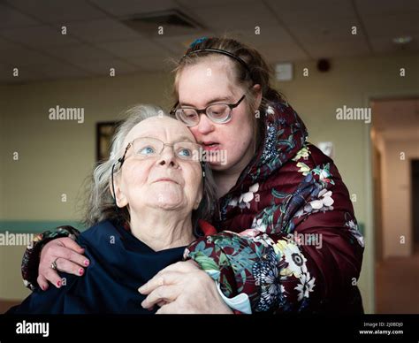 Daughter With Down Syndrome Holding Her Senior Mother Sitting In A