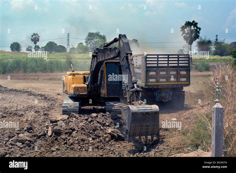 Backhoe Digging To Fill Soil In Dump Truck At Construction Site Stock