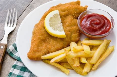 Escalope vienés con patatas fritas en madera Foto Premium