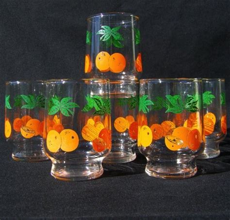 Five Glasses With Oranges Painted On Them Sitting Next To Each Other In Front Of A Black Background